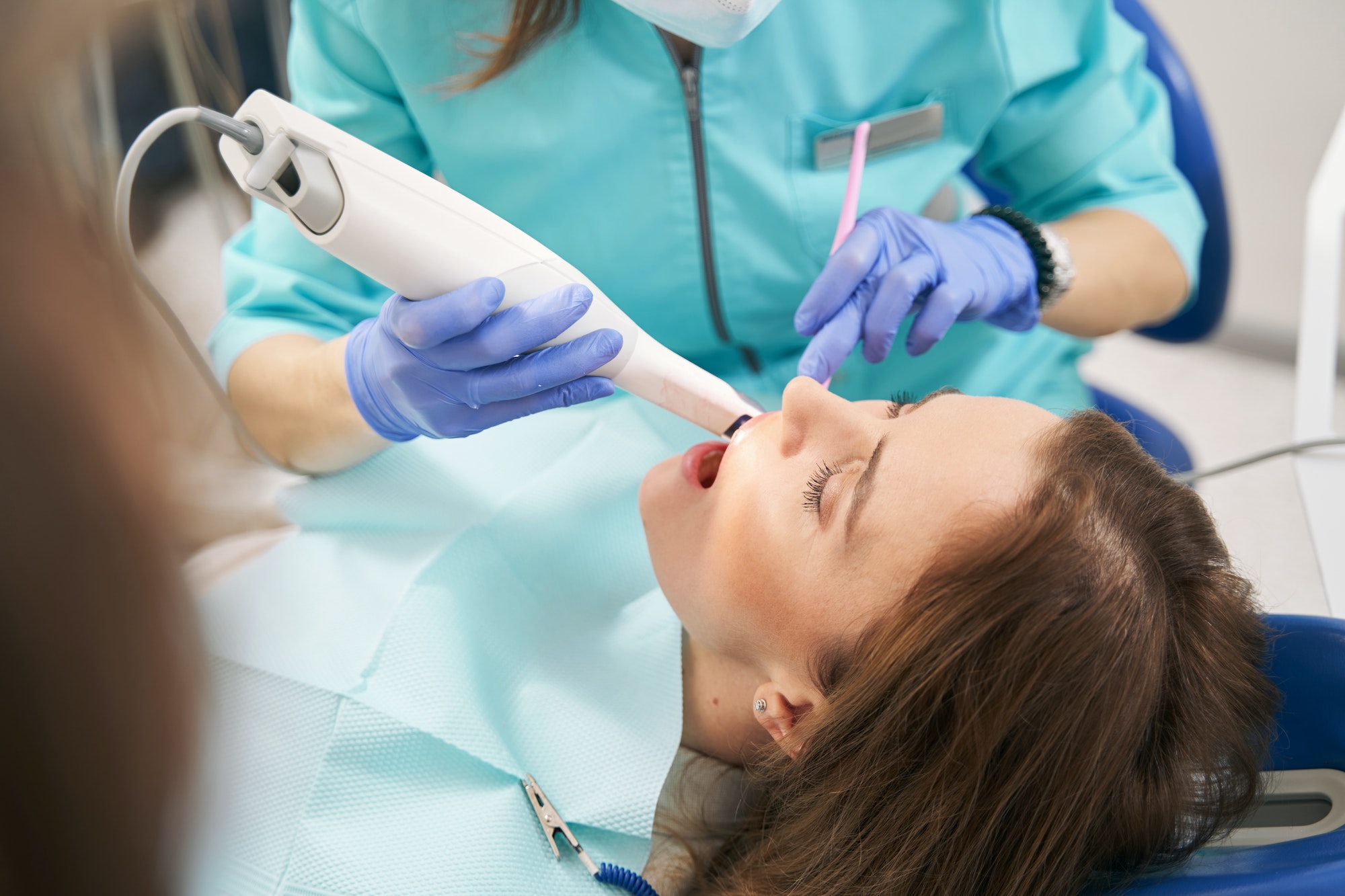 Dentist examining woman teeth with dental scanning device
